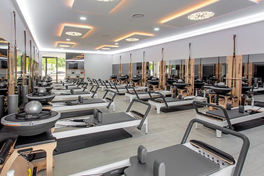 The bright interior of the Live Pilates studio with various empty Pilates machine arranged in rows.