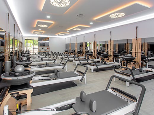 The bright interior of the Live Pilates studio with various empty Pilates machine arranged in rows.