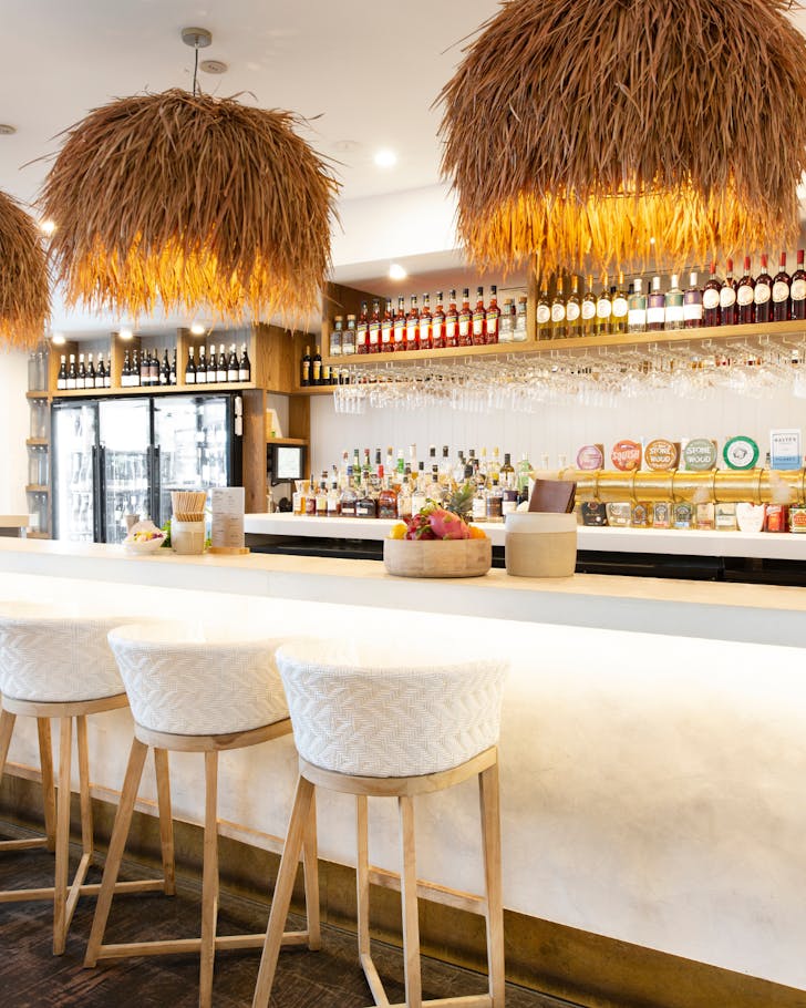 A white bar with rattan light hanging at Loft Bar in Byron Bay