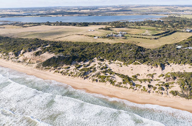a retreat on a stunning coastline, viewed from a drone above the ocean