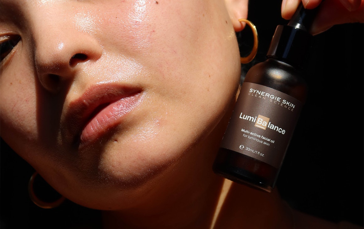 a woman holding a bottle of oil against her face