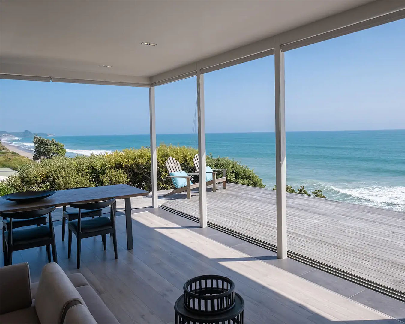 A stunning view from the deck shows blue surf with chairs and comfy sitting areas.