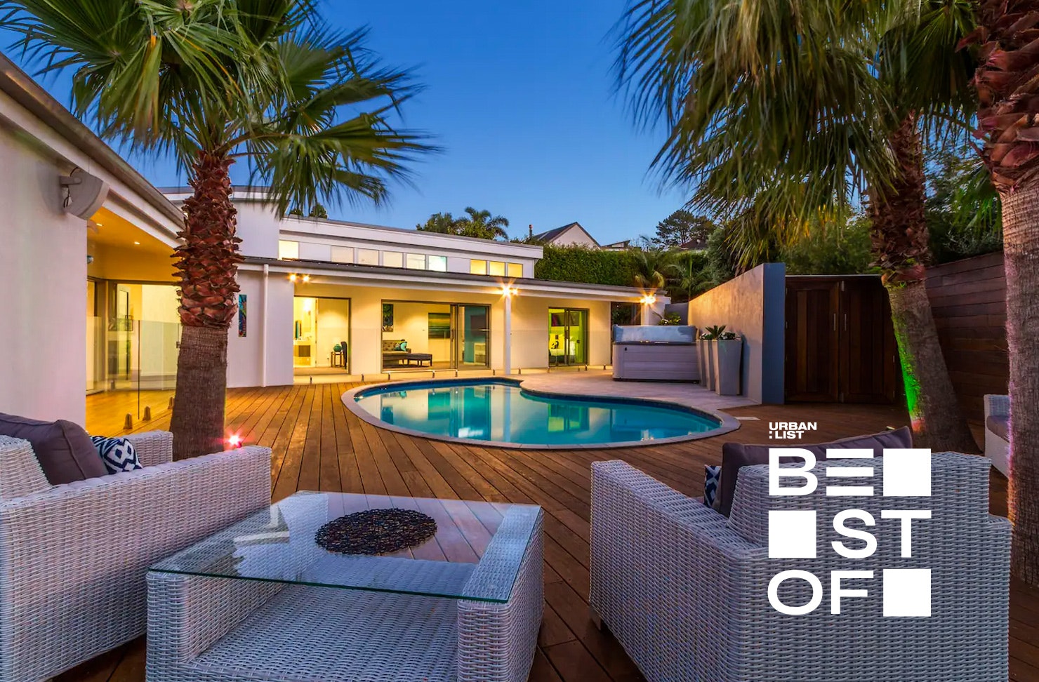 A lovely expansive deck looks out across a pool at dusk in one of the best pet friendly accommodation in NZ.