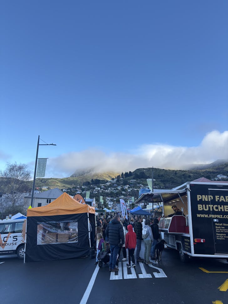 People pack the Lyttelton Market on a chilly day beneath the Port Hills.