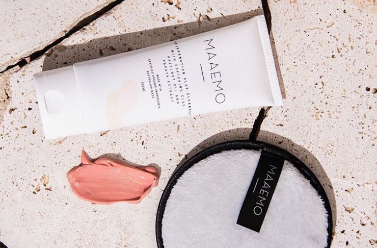 Bottle of MAAEMO pink clay cleanser lying next to a smear of the cleanser and a face cleansing pad