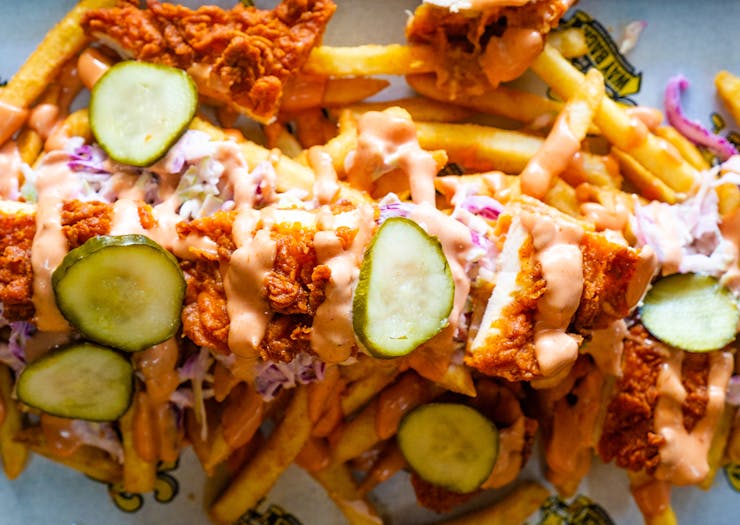 a pile of fries topped with fried chicken and pickles 