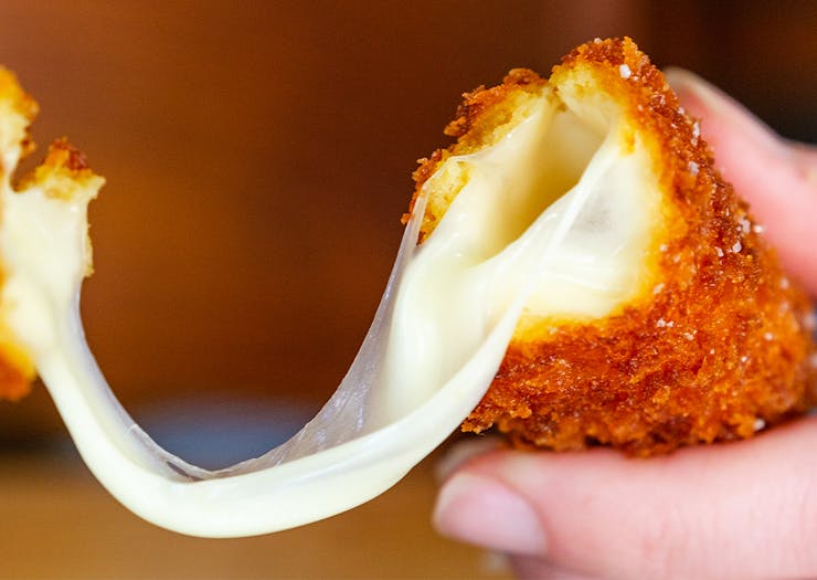 a deep fried mozarella stick being pulled apart