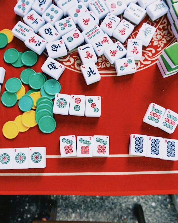 White Mahjong tiles and other pieces on a red table.