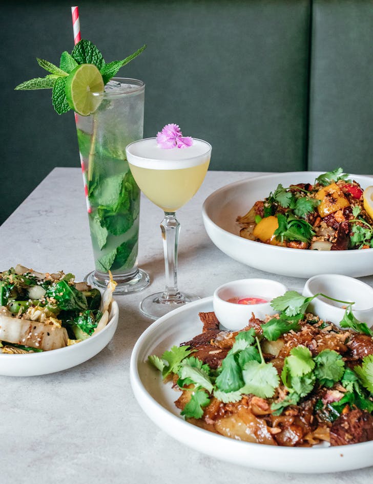 several dishes of food and two cocktails on a table