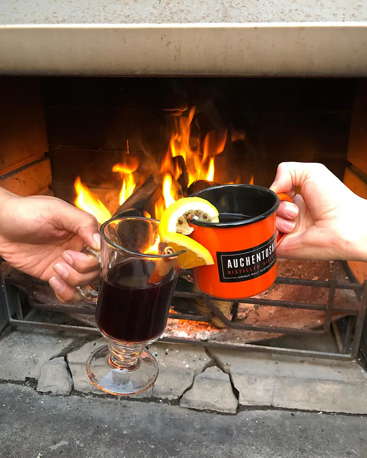A mulled wine cheers in front of an outdoor fireplace at Malt Public House. 