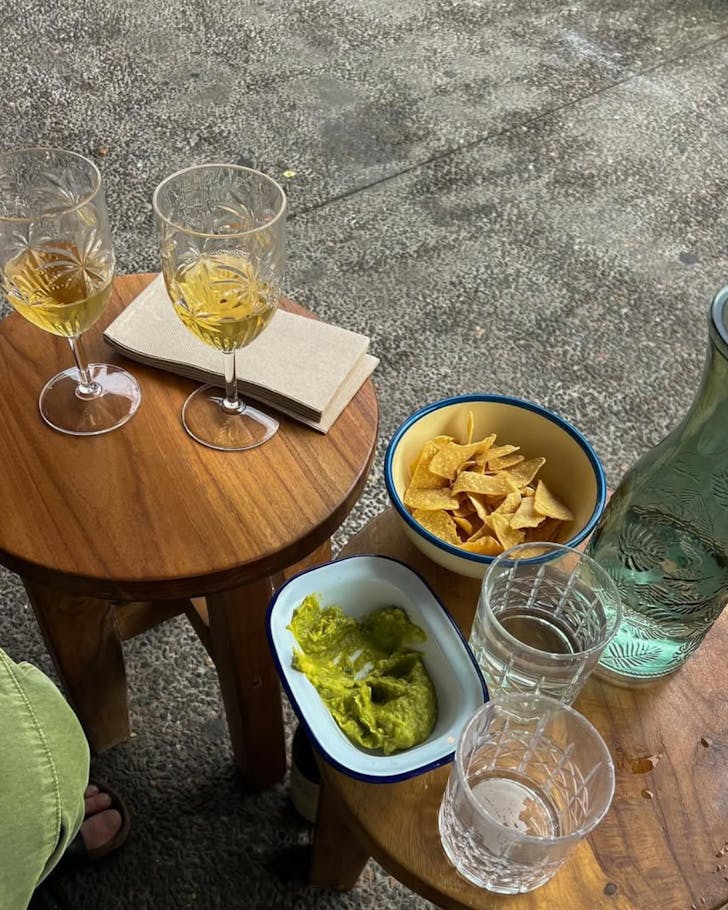 A table at Mami's Bondi with wine glasses, guac and tortilla chips