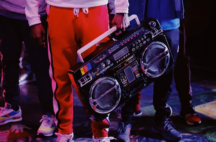 Man in red trackies holds an old school beatbox.