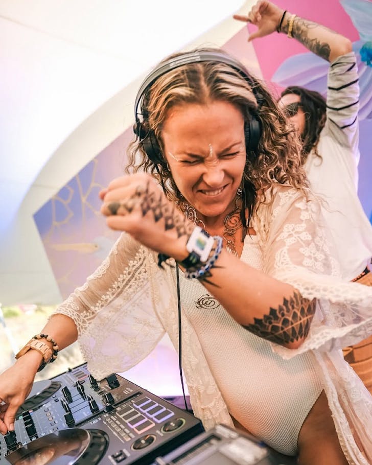 A Manawa Ecstatic DJ throws down on stage with a purple backdrop.