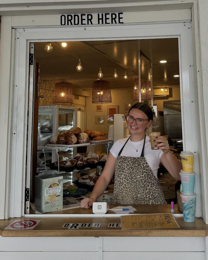 A barista serving coffee out of a window at Coffee Cover