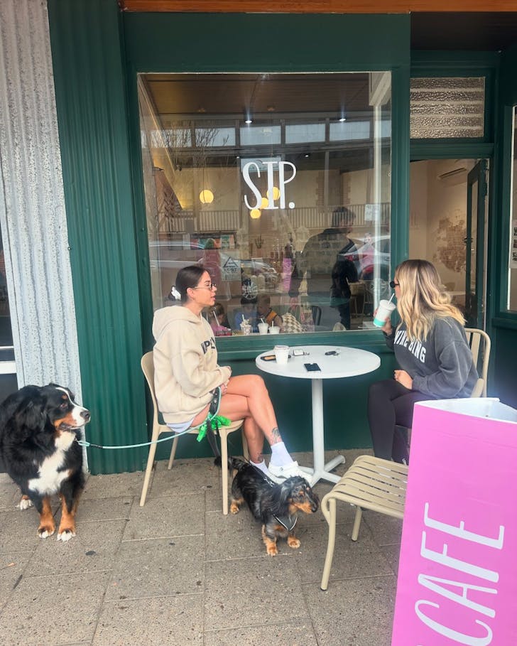 Two women with dogs sitting out front of SIP cafe in Mandurah
