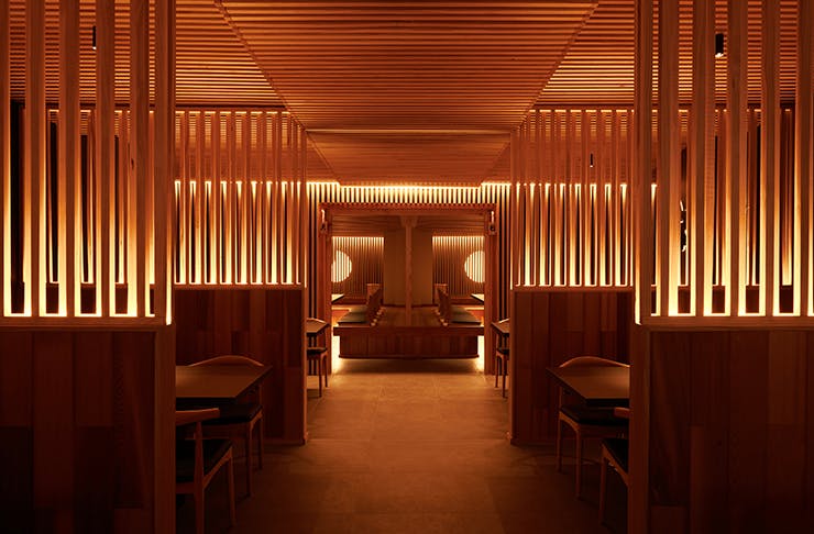An opulent Japanese diner dimly-lit by warm lighting and wooden surroundings.