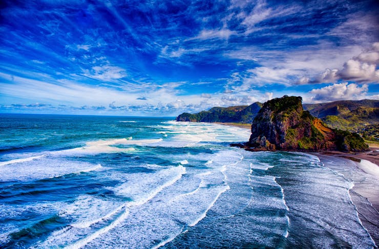 Beautiful blue sky meets an even bluer ocean, as waves crash against the beach. 