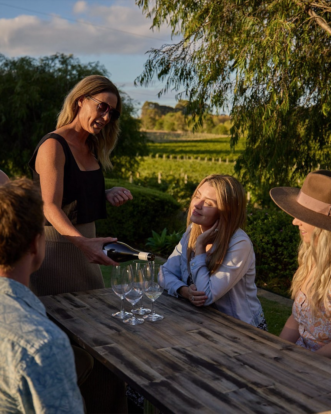 A table of people enjoying wine tastings outdoors at Deep Woods