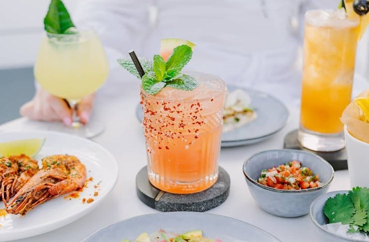 a watermelon margarita on a table amongst plates of food