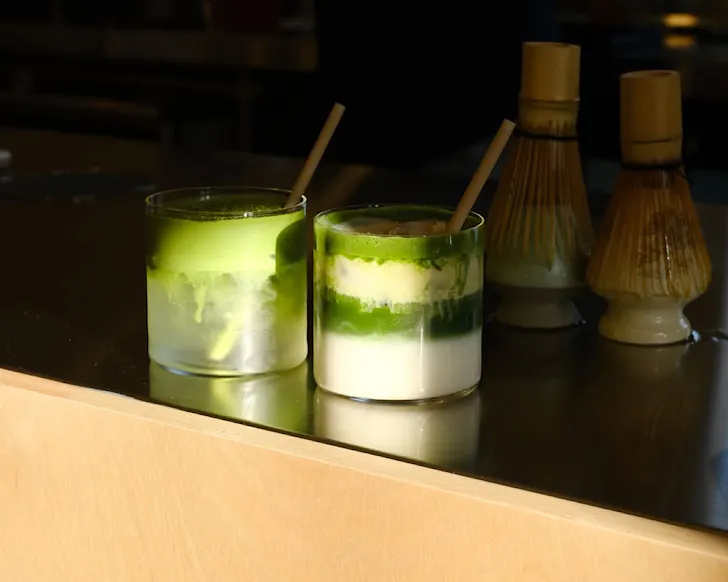 A matcha cold foam and iced matcha sit on the bench at Maru's House.