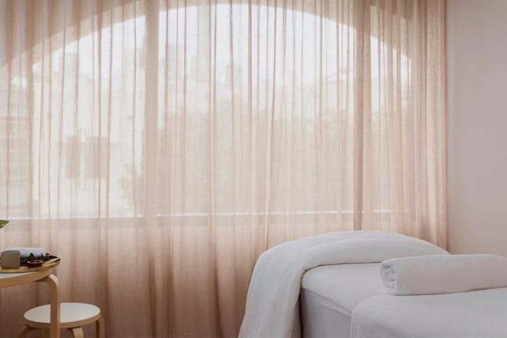 a massage bed in a room with curtained windows