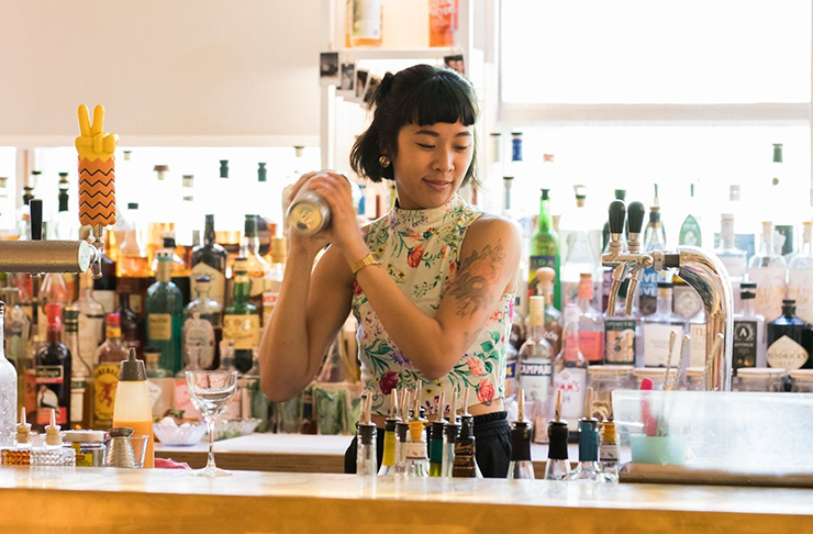 A woman making a cocktail in an outdoor bar.