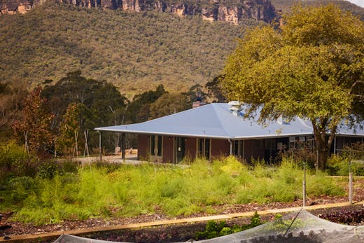Megalong Restaurant and garden with a sandstone escarpment in the background.