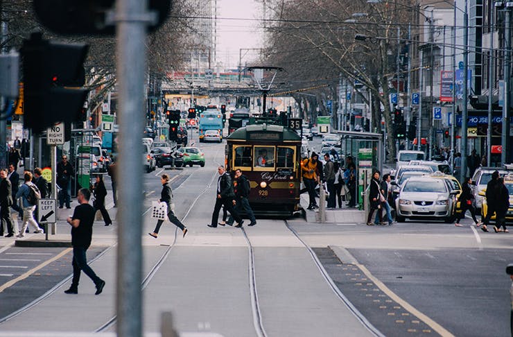A busy Melbourne street with a tram shuttling through the middle.