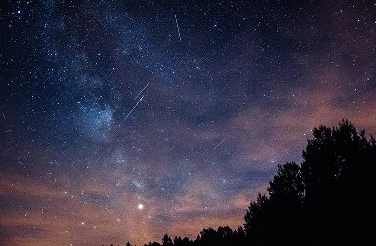 A bue and pink night sky filled with stars and clouds