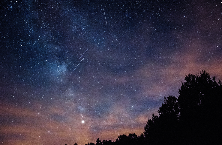 A bue and pink night sky filled with stars and clouds