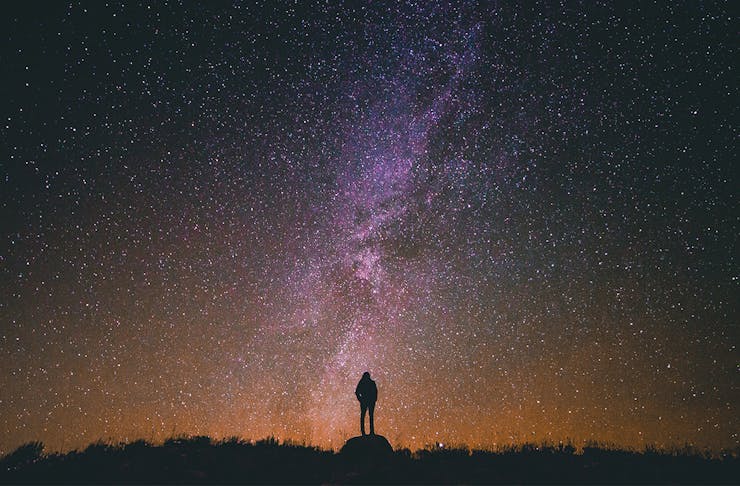 Person in silhouette standing against a star-filled sky