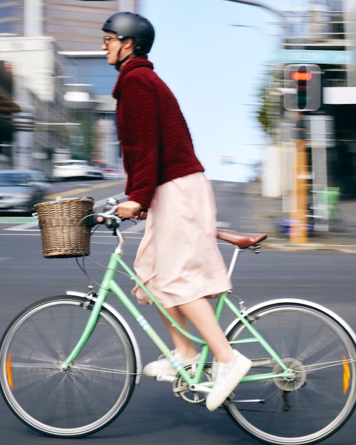 Someone whizzes through the city on a lime green bike with a cane basket.