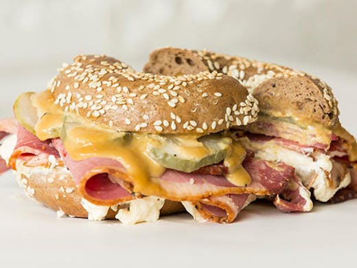 A bagel filled with brisket pastrami and melting cheese.