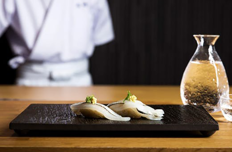 A chef standing behind a small plate of sushi at one of the best restaurants in Richmond.