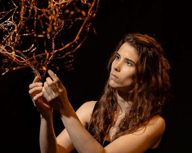 Jody Rallah with one of her golden sculptures in a dark room.