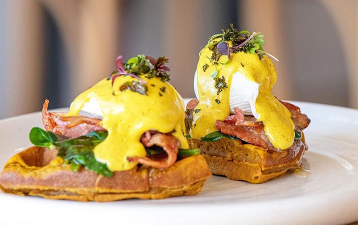 Two quarters of a round waffle topped with eggs benny