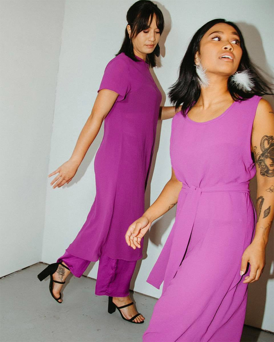 A snapshot of two women wearing pink/purple dresses in different styles.  