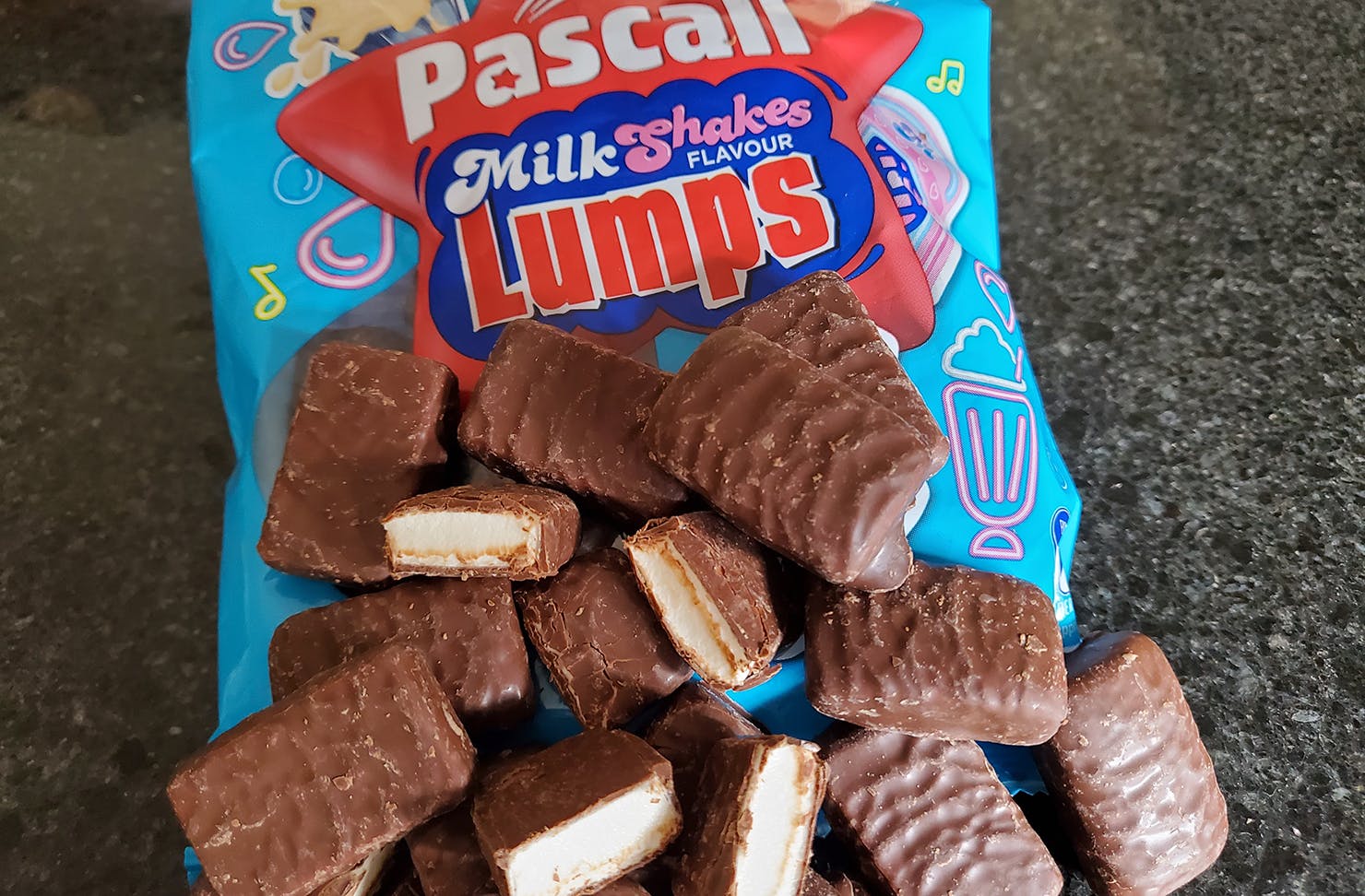 A torn open packet of milkshakes lumps spills onto the table.