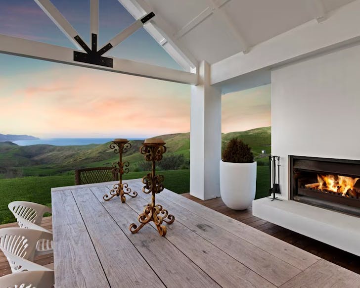 A view from the outdoor entertainment area, of rolling green countryside and a sunset over the ocean.