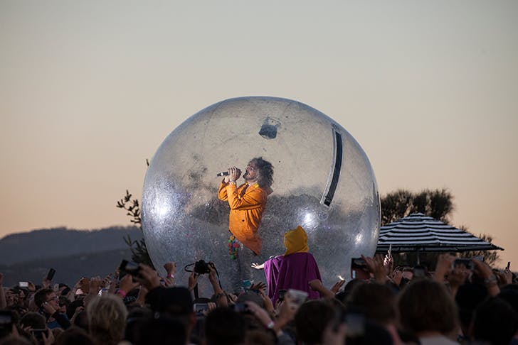 A man singing in a bubble, floating above the crowd.