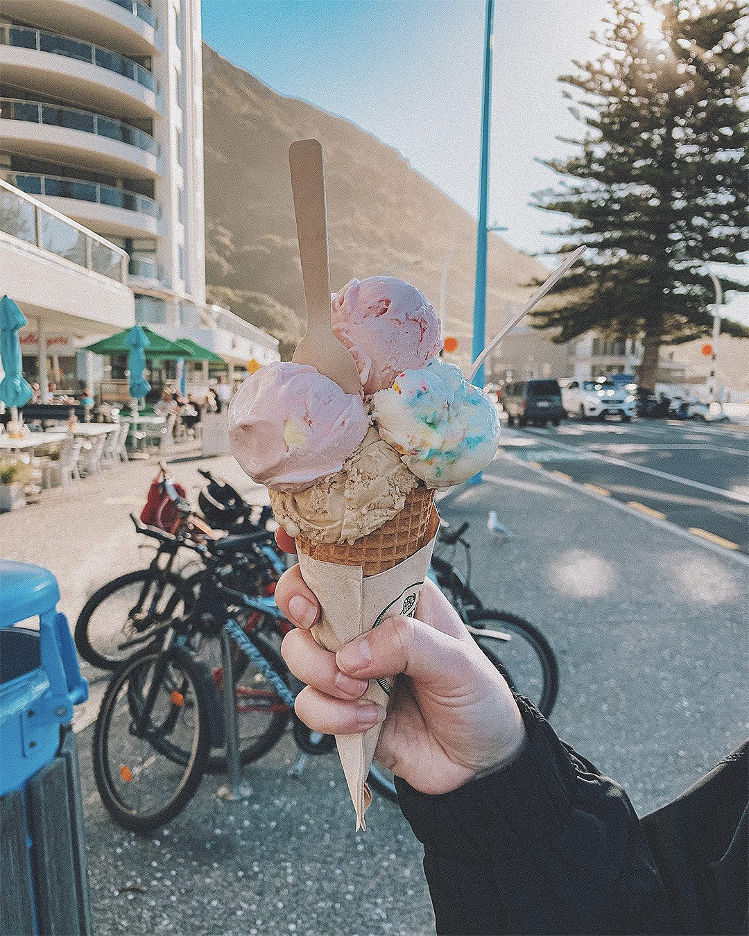 A person holds up an impressive stack of ice cream on a cone from Monte Gelato.