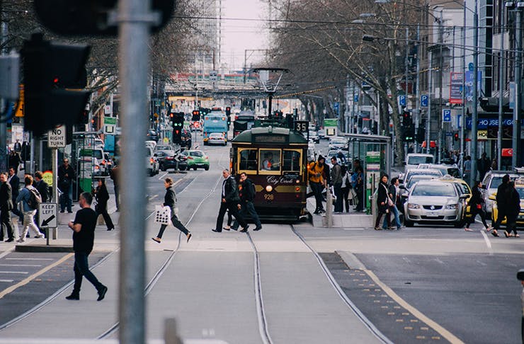 A busy Melbourne CBD street covered in sunlight.