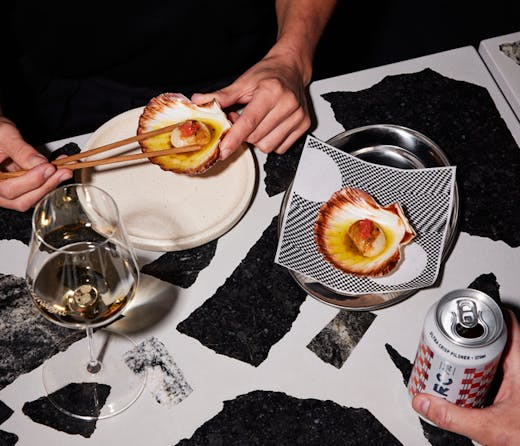 A plate of scallops served on a black and white terrazzo bar. 