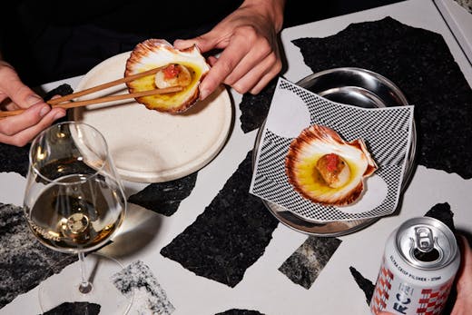 A plate of scallops served on a black and white terrazzo bar.