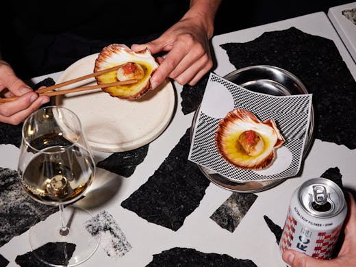 A plate of scallops served on a black and white terrazzo bar. 