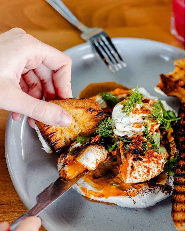 Someone digging into a bowl of eggs at a Mother's Day Breakfast spot in Perth