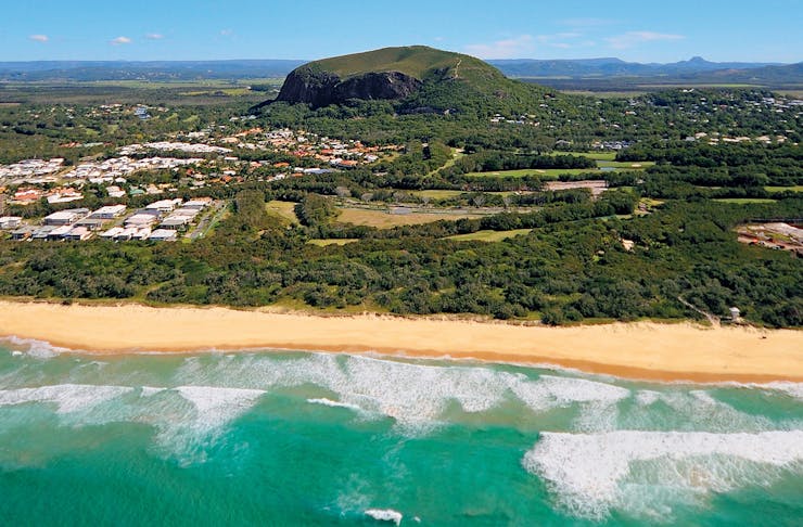 Mount Coolum juts out of the Sunshine Coast landscape, with the ocean in the foreground. 