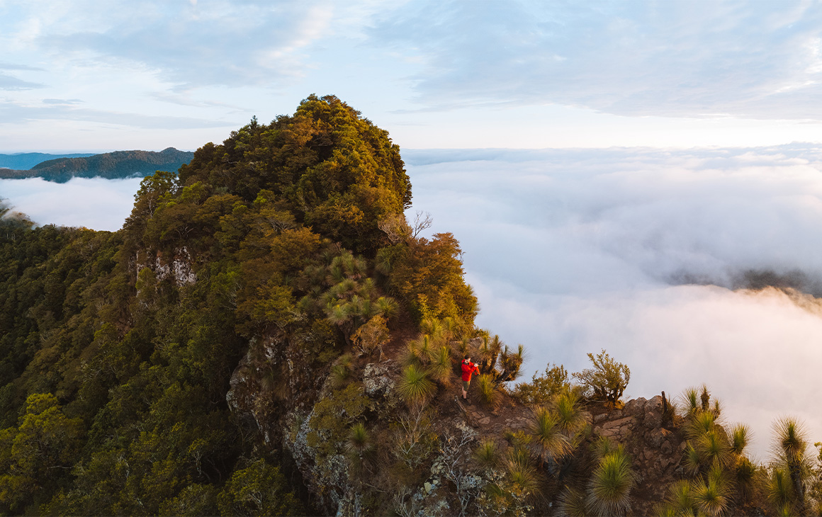 a person hiking a mountain peak above the clouds