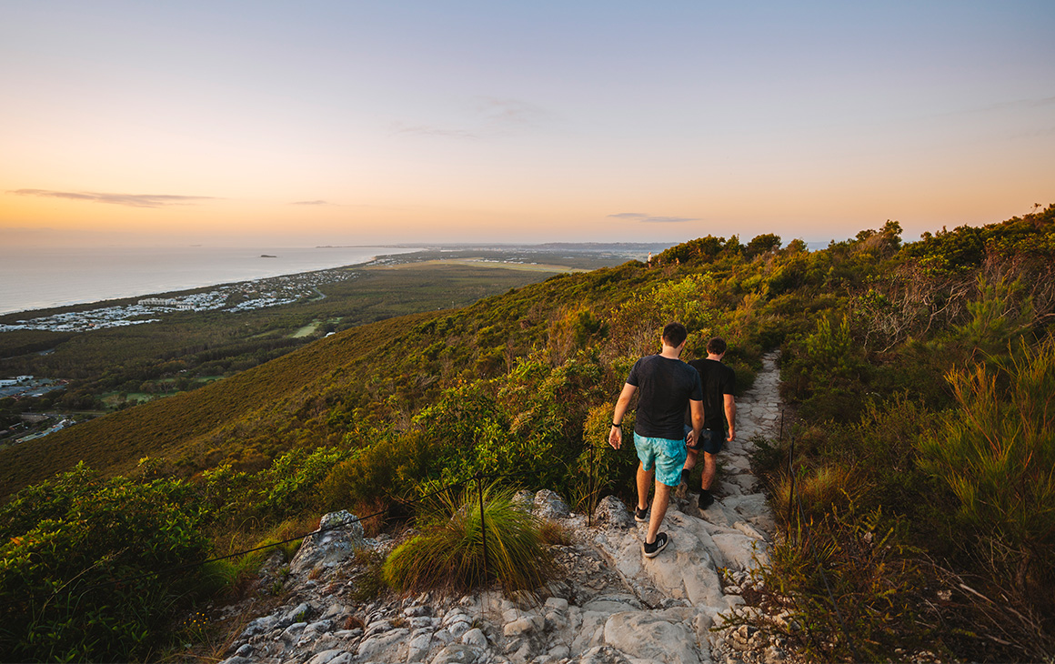people hiking mt coolum, with views to the ocean
