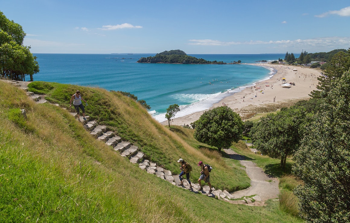 A view of Mauao and Main Beach as people go up and down the steps to the summit on a fine summer's day.